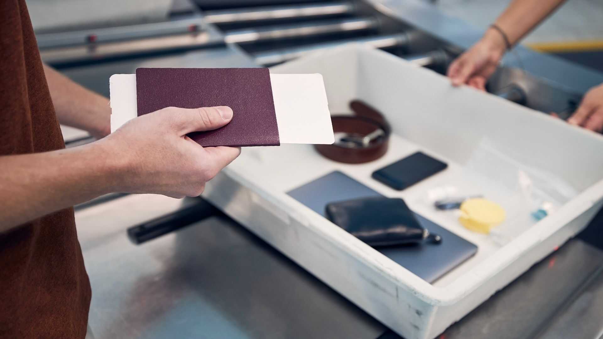 Passager tenant passeport et carte d'embarquement à un point de contrôle de sûreté fast-track pour un vol affrété en groupe.